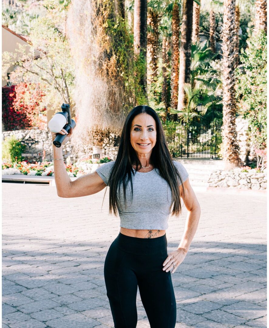 Woman in workout attire holding a dumbbell outdoors.